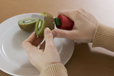 Hände schälen eine Kiwi, Gesunde Ernährung