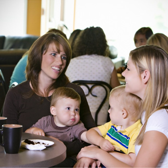 Mütter mit Ihren Kindern sitzem im Café und unterhalten sich