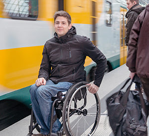 Junger Mann im Rollstuhl auf dem Bahnsteig